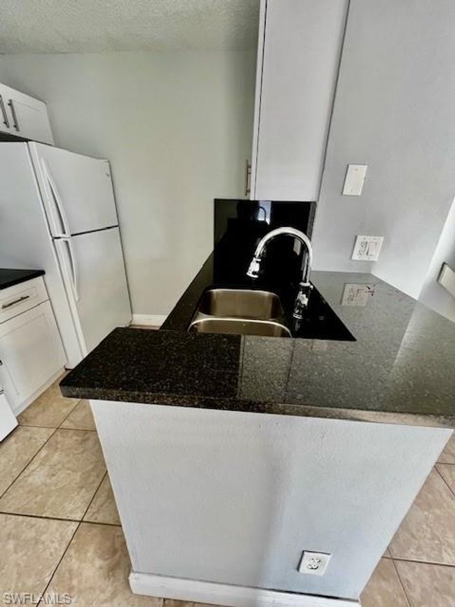 Kitchen featuring a peninsula, a sink, white cabinets, and freestanding refrigerator | Image 11