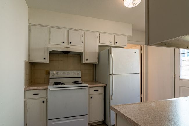 1214 Hunt - Kitchen with decorative backsplash, light countertops, white appliances, under cabinet range hood, and white cabinetry | Image 5