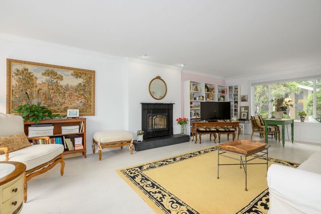 Living room with crown molding, a fireplace with raised hearth, and built in shelves | Image 4