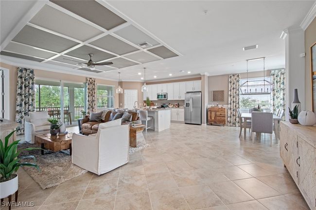Living area with coffered ceiling, a healthy amount of sunlight, ceiling fan with notable chandelier, and visible vents | Image 25