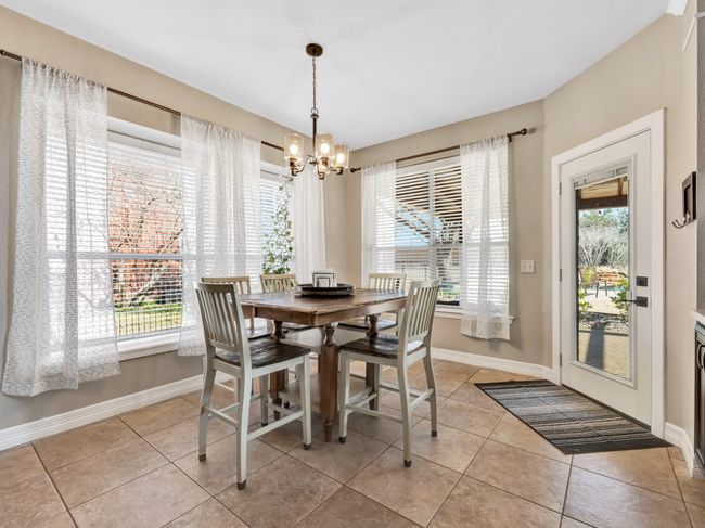 Dining room featuring light tile patterned flooring, a notable chandelier, and baseboards | Image 13