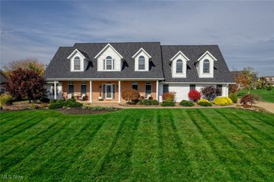 New england style home with a front lawn and covered porch | Image 1