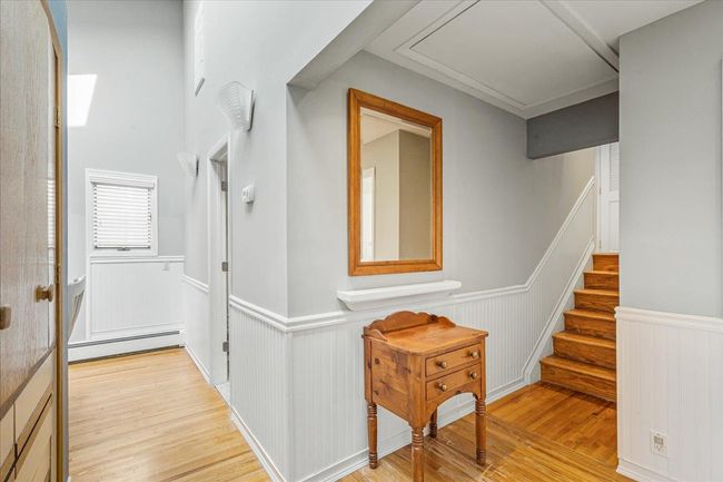 Corridor featuring a baseboard heating unit, wainscoting, wood finished floors, stairs, and a decorative wall | Image 20
