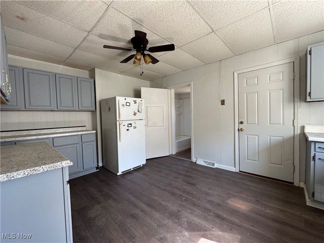 Kitchen with dark wood-style floors, light countertops, visible vents, and freestanding refrigerator | Image 17