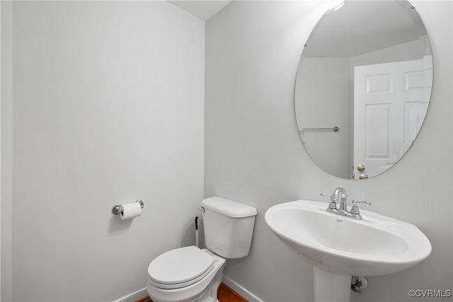 Half bathroom with baseboards, toilet, and a sink | Image 23