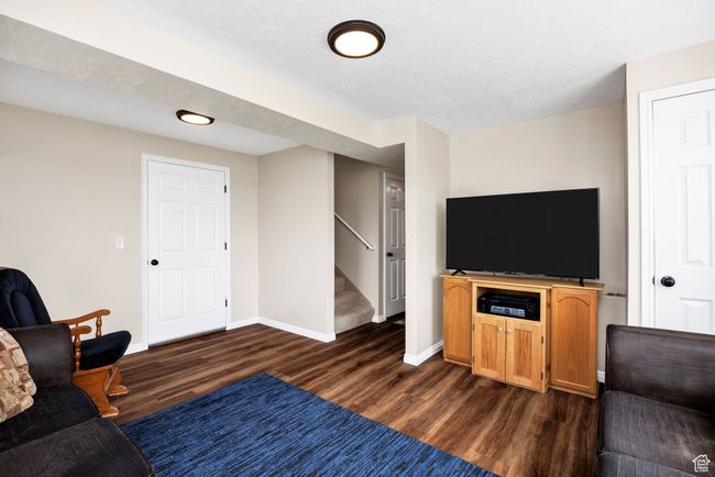 Basement Living room featuring dark wood-style flooring, stairs, and baseboards | Image 19