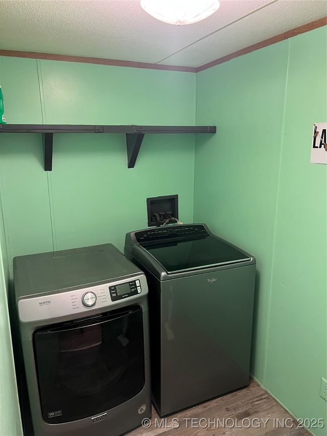 Clothes washing area with washer and clothes dryer, light wood-style flooring, and a textured ceiling | Image 26