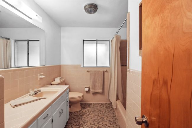 Full bath with a wainscoted wall, curtained shower, toilet, and tile walls | Image 26