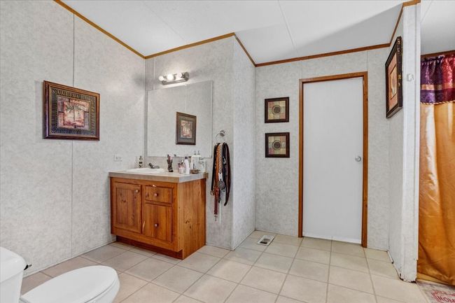 Full bath with toilet, tile patterned flooring, ornamental molding, and vanity | Image 17
