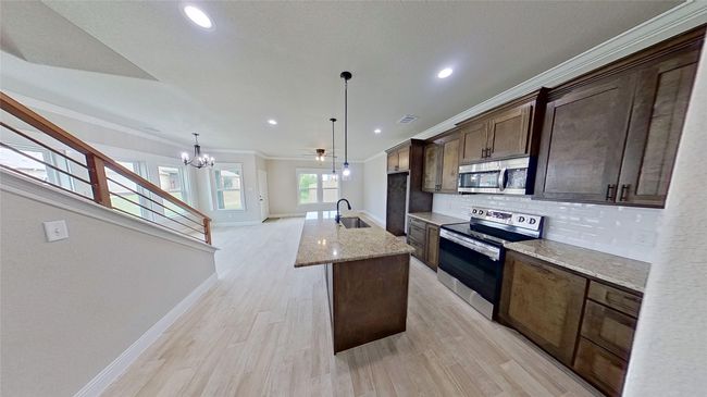 Kitchen featuring a kitchen island with sink, a sink, ornamental molding, appliances with stainless steel finishes, and decorative backsplash | Image 16