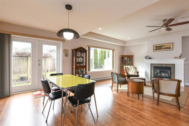 Living area featuring a tiled fireplace, wood finished floors, a baseboard radiator, a ceiling fan, and recessed lighting | Image 6