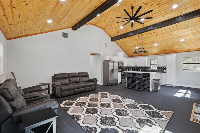 Living area with visible vents, baseboards, wooden ceiling, beamed ceiling, and high vaulted ceiling | Image 15