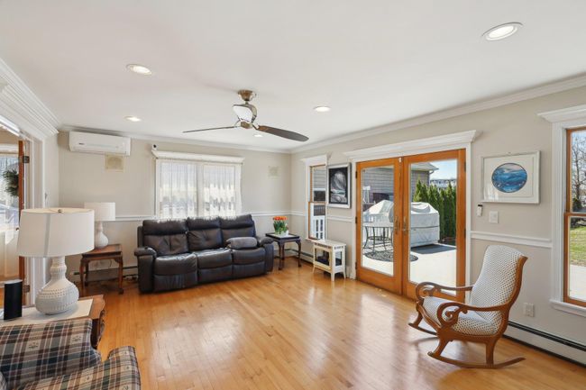 Living room with ornamental molding, a wall mounted AC, baseboard heating, light wood finished floors, and french doors | Image 9