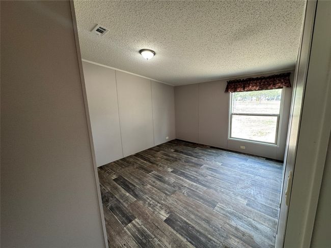Unfurnished room with dark wood finished floors, a textured ceiling, and visible vents | Image 12