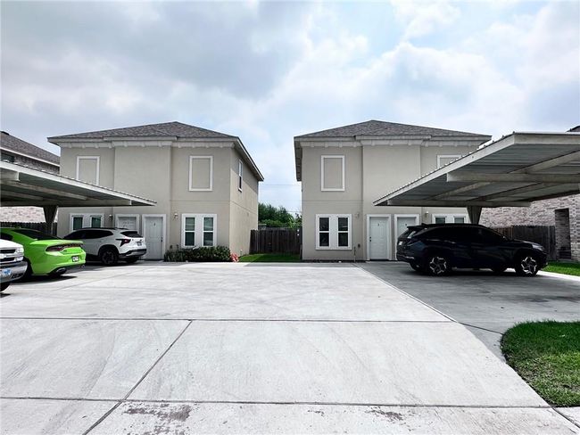 View of side of property featuring covered parking, stucco siding, fence, and roof with shingles | Image 4
