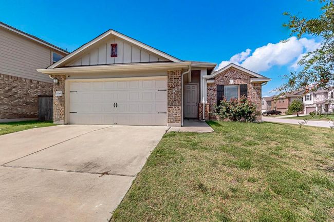 Ranch-style house featuring board and batten siding, driveway, a front yard, a garage, and brick siding | Image 4