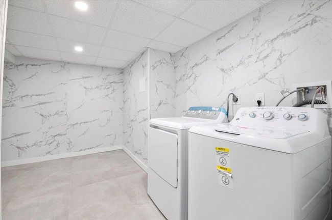 Washroom featuring recessed lighting, washer and clothes dryer, and stone wall | Image 25