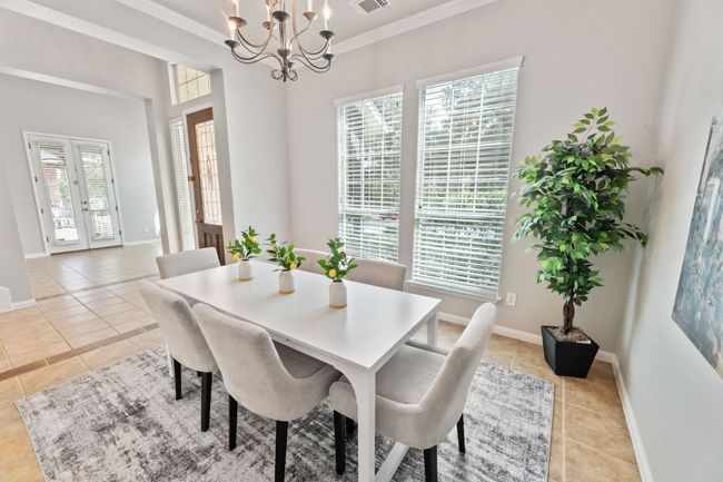 Dining room featuring light tile patterned floors, ornamental molding, and a chandelier | Image 9