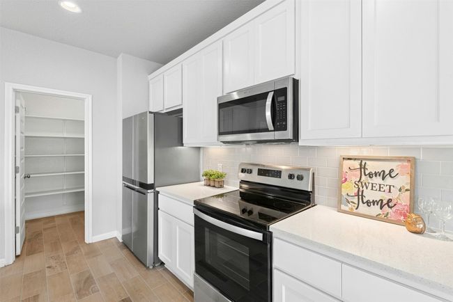 Kitchen featuring stainless steel appliances, white cabinetry, tasteful backsplash, light stone counters, and recessed lighting | Image 14