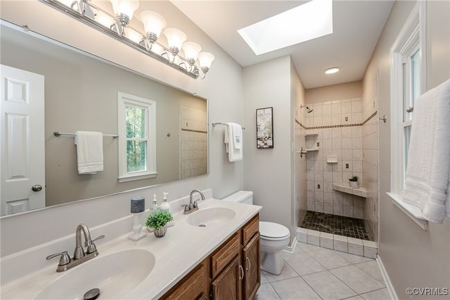 Ensuite bathroom with tile patterned floors, a skylight, toilet, and a sink | Image 33