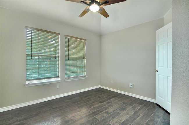 Unfurnished room with ceiling fan, dark hardwood / wood-style floors, vaulted ceiling, and a wealth of natural light | Image 18
