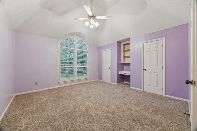 The third of the secondary bedrooms is 14’x13’ and includes two closets, a built-in desk and bookcase above, a large arched window overlooking the front yard, and ensuite bath. | Image 29