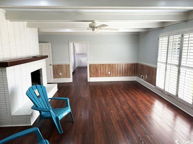 Unfurnished room with a brick fireplace, beamed ceiling, dark hardwood / wood-style floors, and ceiling fan | Image 12
