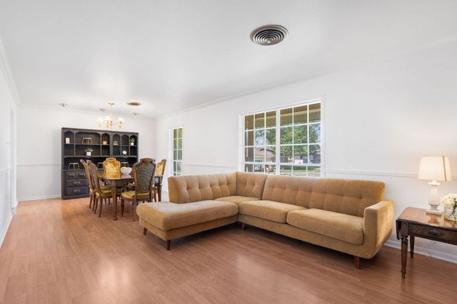 Living area in the front of the home with a dining room and ornamental molding, and laminate flooring | Image 5