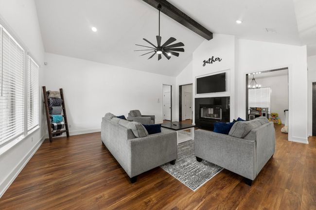 Living room featuring dark wood-type flooring, ceiling fan with notable chandelier, baseboards, and beam ceiling | Image 11