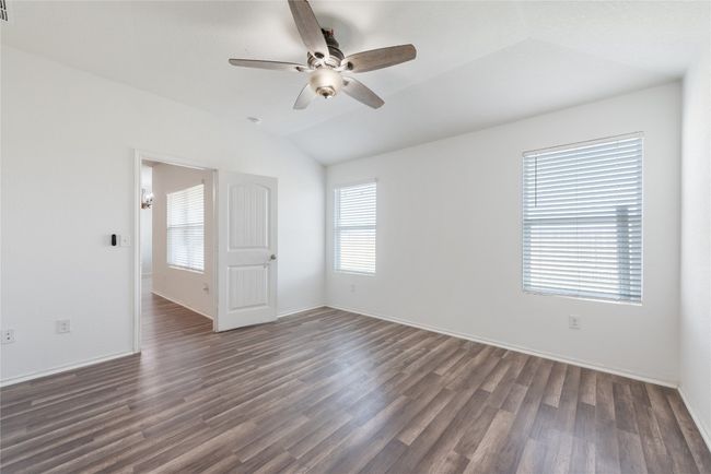 Empty room with vaulted ceiling, dark wood finished floors, and ceiling fan | Image 11