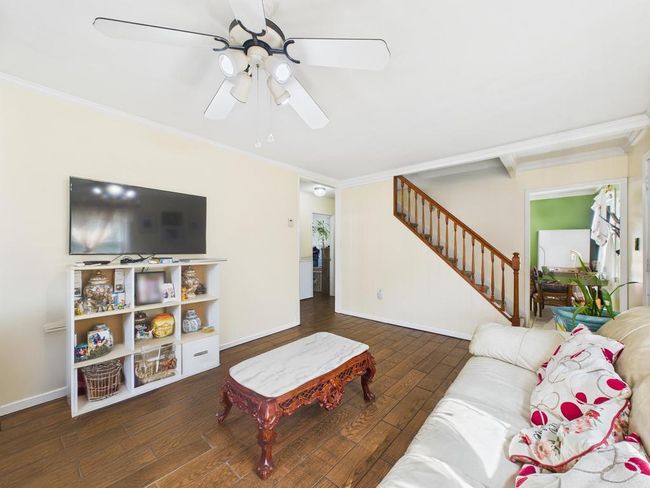 Living room featuring a ceiling fan, stairs, crown molding, and hardwood / wood-style flooring | Image 9