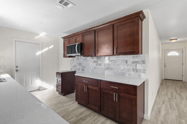 Kitchen featuring light hardwood / wood-style floors, tasteful backsplash, and dark brown cabinetry | Image 6