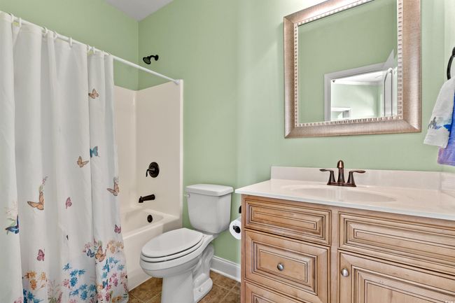 Full bath with tile patterned flooring, vanity, shower / tub combo with curtain, toilet, and baseboards | Image 7