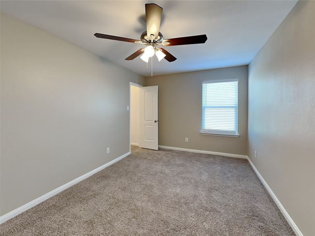 Carpeted empty room with ceiling fan and baseboards | Image 11