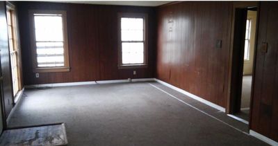 Carpeted empty room with plenty of natural light and wooden walls | Image 2