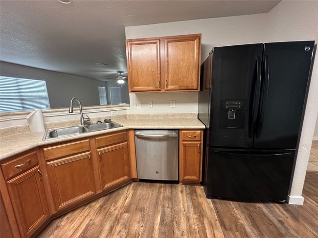 Kitchen featuring black fridge, wood finished floors, dishwasher, and ceiling fan | Image 12