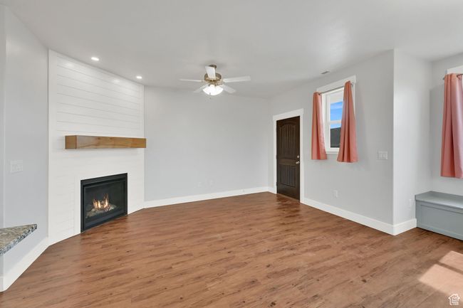 Unfurnished living room featuring a ceiling fan, wood finished floors, recessed lighting, and a large fireplace | Image 46