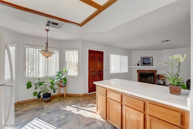 Kitchen featuring visible vents, baseboards, freestanding refrigerator, a textured ceiling, and a fireplace | Image 13