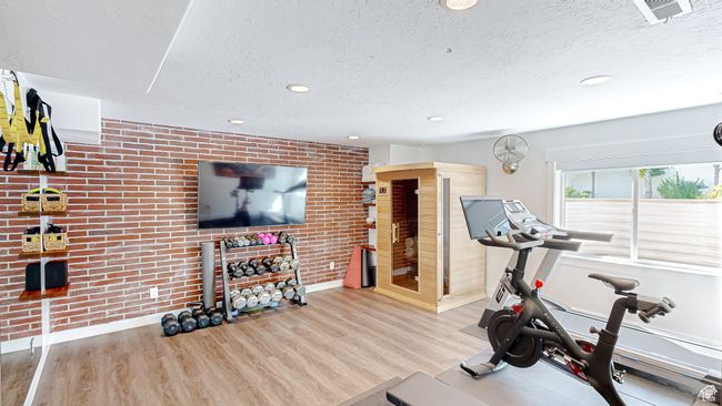 Workout area with visible vents, a textured ceiling, brick wall, and wood finished floors | Image 37