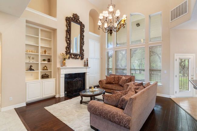 Living room featuring a high ceiling, dark wood-type flooring, a fireplace with flush hearth, a chandelier, and baseboards | Image 12