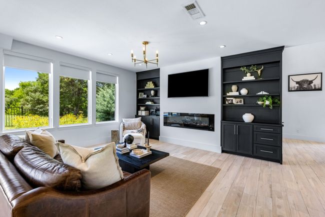 Living area featuring a chandelier, light wood-style floors, a glass covered fireplace, recessed lighting, and built in features-Amazing views! | Image 8