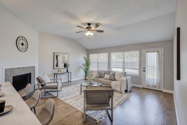 Living room featuring a ceiling fan, a fireplace, lofted ceiling, baseboards, and wood finished floors | Image 16