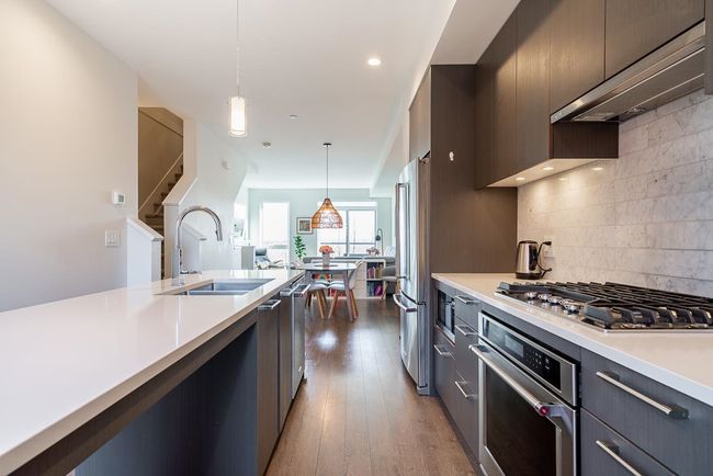 Kitchen featuring pendant lighting, a sink, wood finished floors, appliances with stainless steel finishes, and light countertops | Image 6