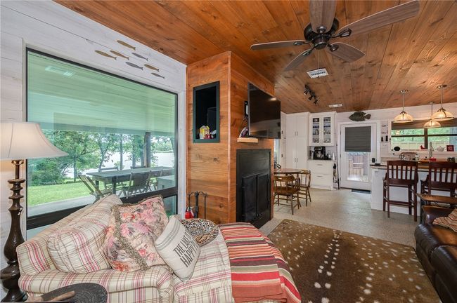 Living area with wooden ceiling, healthy amount of natural light, ceiling fan, and a fireplace | Image 41