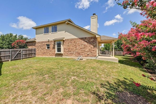 Rear view of property featuring brick siding, a patio, a fenced backyard, and a chimney | Image 26