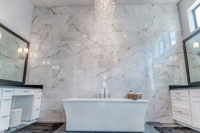 Full bathroom with a soaking tub, tile walls, an inviting chandelier, and vanity | Image 16
