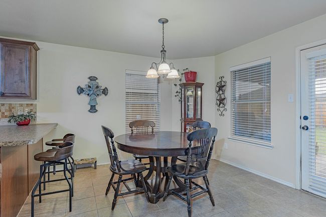 Dining area featuring light tile patterned flooring, baseboards, and a chandelier | Image 9