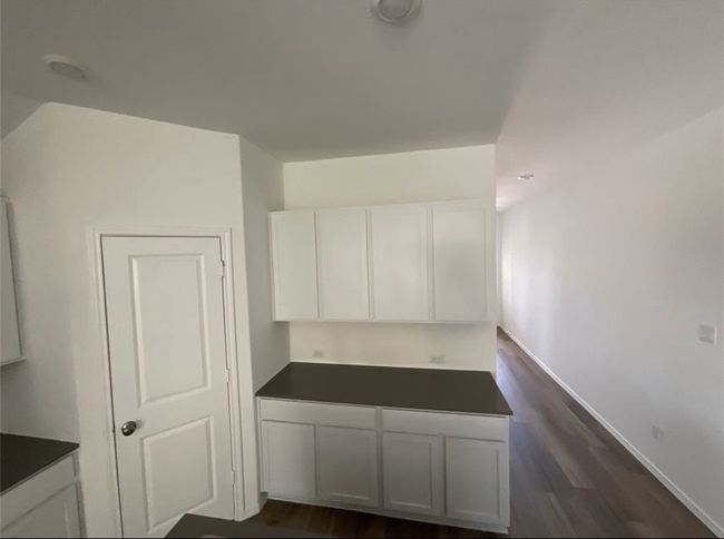 Kitchen with white cabinetry, dark countertops, dark wood-type flooring, and baseboards | Image 8
