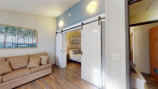Living area featuring a barn door and wood finished floors | Image 16