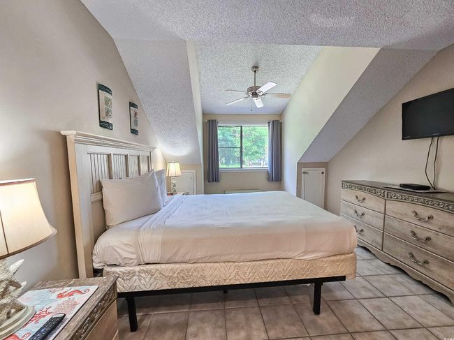 Bedroom featuring a textured ceiling, vaulted ceiling, and ceiling fan | Image 30